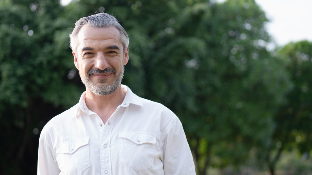 Portrait shot of happy, successful, attractive bearded middle-aged man smiling with a confident look